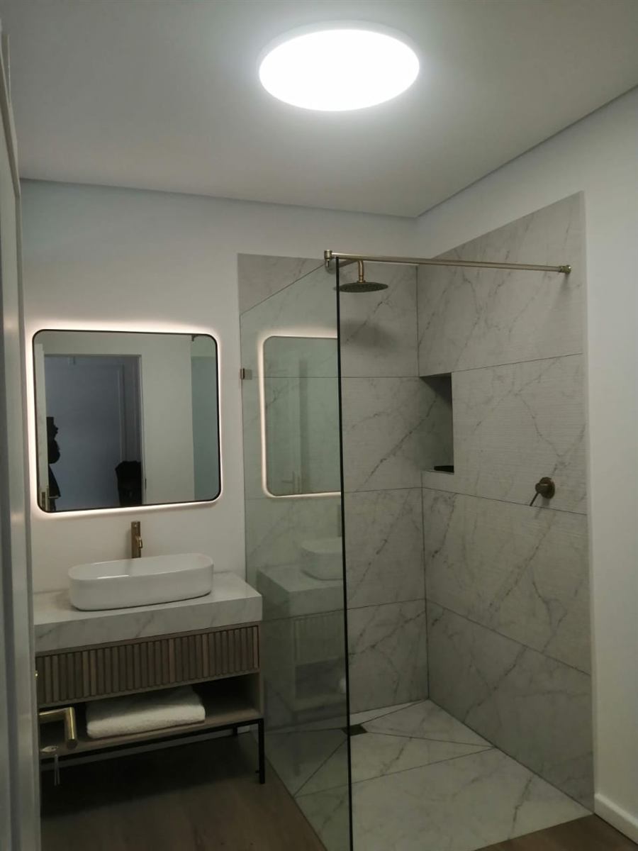 Bathroom with an LED backlit mirror and a round LED ceiling panel