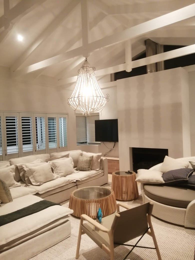 Living room with a beaded chandelier and downlights under a vaulted white ceiling